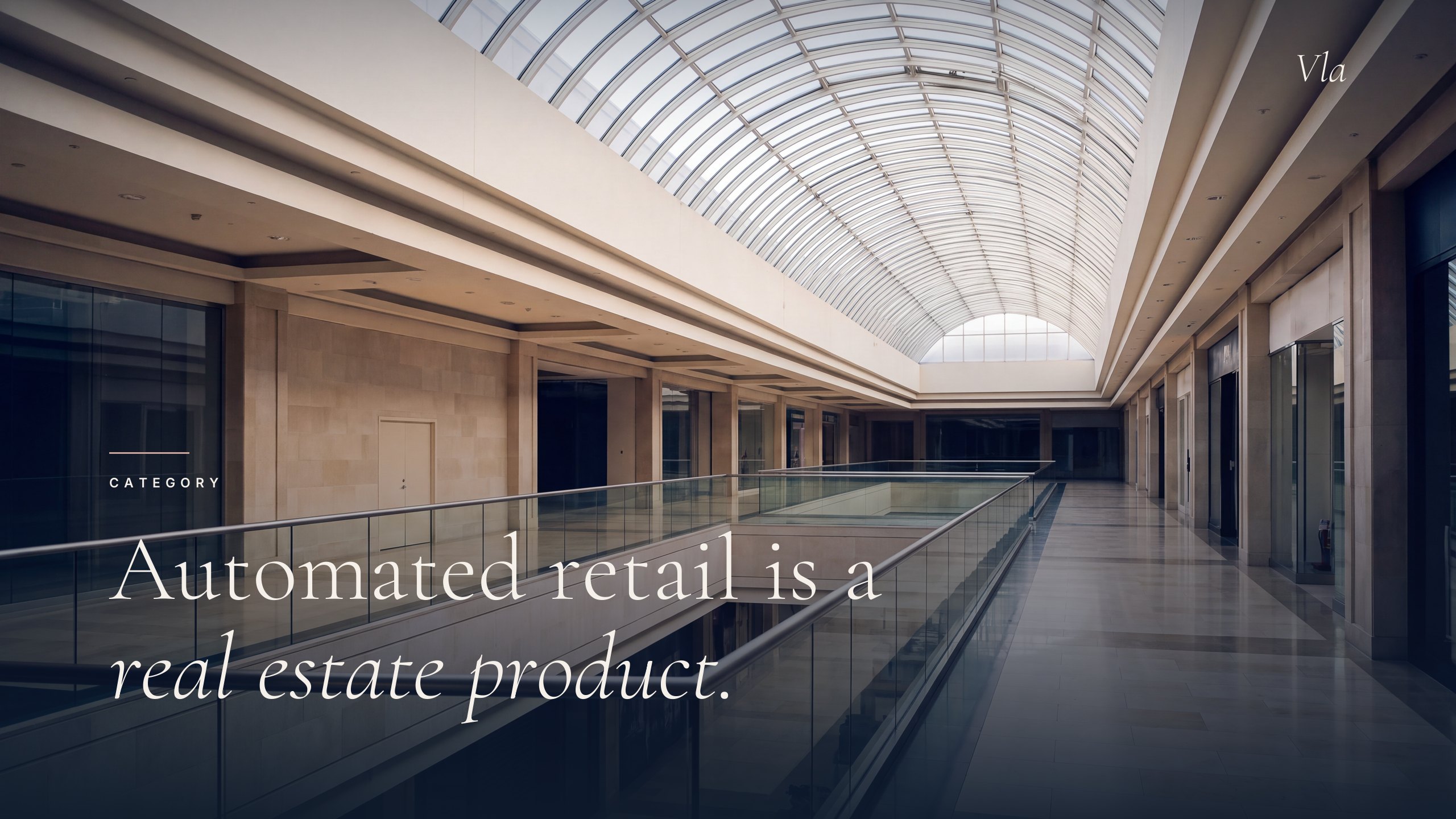 An empty premium shopping centre concourse seen from an upper level, lit by a glazed barrel skylight.